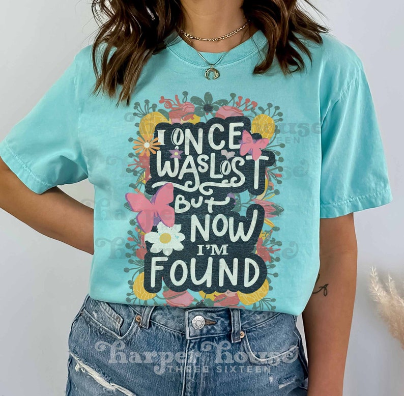 May include: A turquoise blue t-shirt with a floral design and the text "I once was lost but now I'm found".