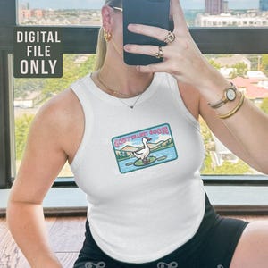 K&ouml;nnte beinhalten: Wei&szlig;es Tanktop mit einer Grafik einer Gans auf einer Seerose, mit dem Text "GOD'S SILLIEST GOOSE". Der Text "DIGITAL FILE ONLY" befindet sich in der oberen linken Ecke. Das Tanktop wird von einer Person getragen.