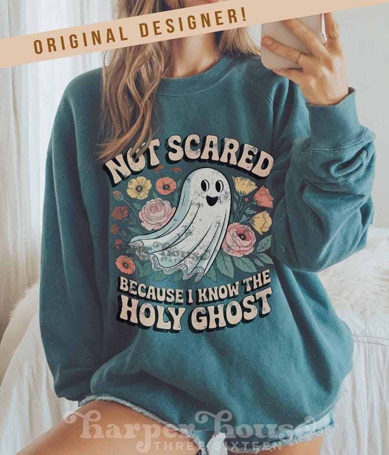 May include: Teal-colored sweatshirt with the text "NOT SCARED BECAUSE I KNOW THE HOLY GHOST" and a cartoon ghost illustration. The design includes floral elements in various colors. The brand name "Harper House Three Sixteen" is at the bottom.