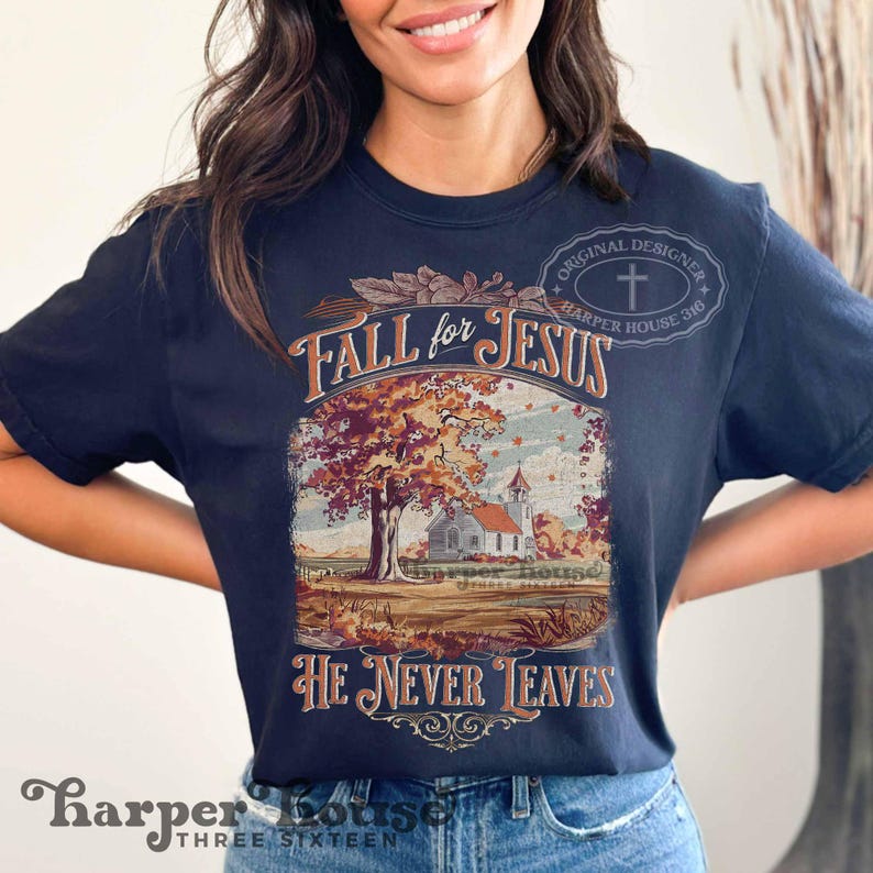 May include: Navy blue t-shirt with a fall-themed graphic. The graphic features a church, a tree with autumn leaves, and the text "Fall for Jesus" and "He Never Leaves". The shirt also has the text "Harper House Three Sixteen".