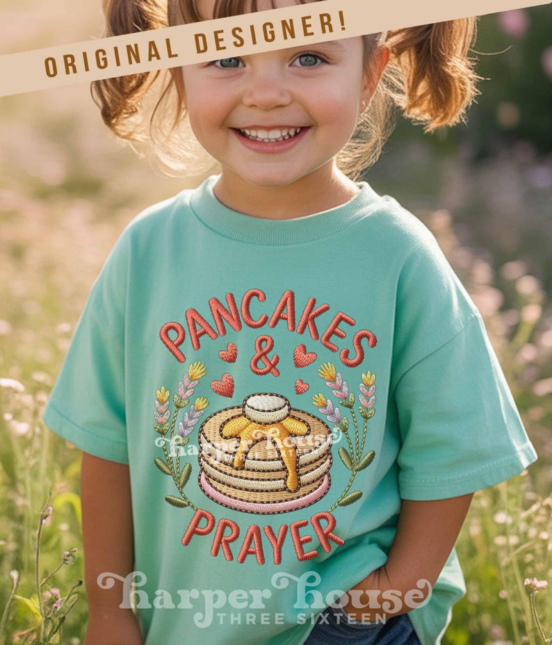 May include: A light teal t-shirt with the embroidered words "PANCAKES & PRAYER" in red script. The design includes a stack of pancakes with syrup, hearts, and floral accents. The brand name "Harper House" is at the bottom.