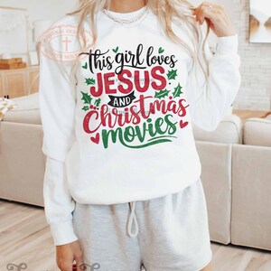 May include: White sweatshirt with the text "This girl loves Jesus and Christmas movies" in red and green lettering with holly leaves.