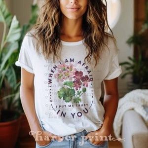 May include: White t-shirt with a floral design and the text "WHEN I AM AFRAID I PUT MY TRUST IN YOU" and "PSALM 56:3".