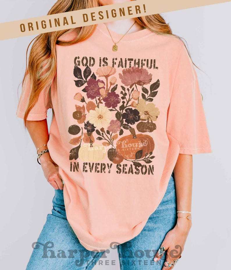 May include: Peach-colored t-shirt with a floral and pumpkin graphic. The design includes the text "GOD IS FAITHFUL IN EVERY SEASON." The shirt has short sleeves and a relaxed fit. The words "ORIGINAL DESIGNER!" are at the top.