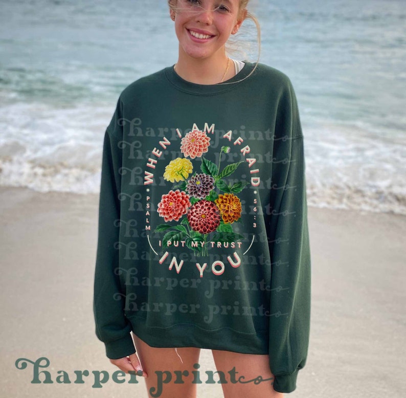 May include: A dark green sweatshirt with a floral design and the text "WHEN I AM AFRAID *PSALM 56:3 I PUT MY TRUST IN YOU" in a circle.