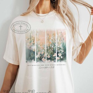 May include: A white t-shirt with a floral design and the text "His mercies are new every morning, Lamentations 3:23".