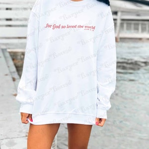 May include: White sweatshirt with the text "For God so loved the world" in pink lettering and the text "John 3:16" in smaller pink lettering.