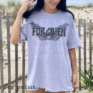 May include: Gray t-shirt with a black graphic of wings and the word "FORGIVEN" printed on the front.
