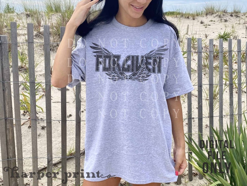May include: Gray t-shirt with a black graphic of wings and the word "FORGIVEN" printed on the front.