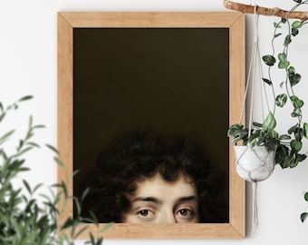 May include: A framed painting of a person's face peeking out from behind a dark background. The person has dark curly hair and brown eyes. The frame is made of light wood.