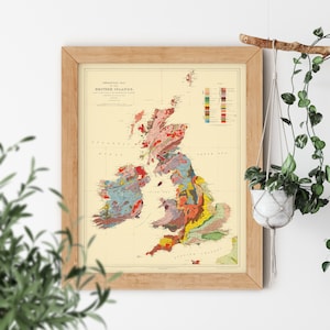 May include: A vintage geological map of the British Isles, showing the different rock formations in various colors. The map is framed in a light wood frame and is hanging on a white wall.