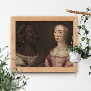 May include: An oil painting in a wooden frame depicts two women. The woman on the left has dark skin and wears a white dress. The woman on the right has fair skin and wears a pink dress. Both women have long dark hair.