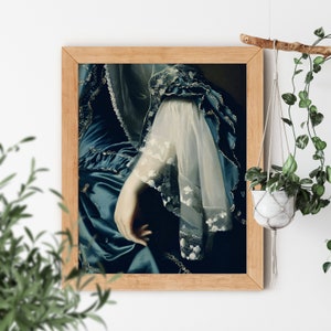 May include: A framed painting of a woman wearing a blue and white dress with lace detailing. The woman's hand is visible, resting on her lap.