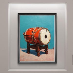 Op de afbeelding: Een ingelijst schilderij van een rode trommel met witte trommelvellen, vastgezet met touw, op een donkerhouten standaard. De achtergrond is turquoise. Het kunstwerk wordt gepresenteerd in een witte lijst, ideaal voor interieurdecoratie.
