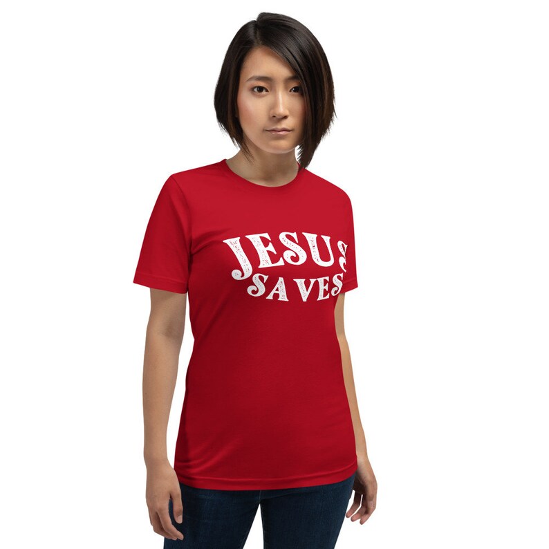 Pu&ograve; includere: Maglietta rossa a maniche corte con testo bianco che dice "JESUS SAVES".