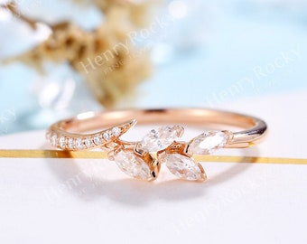 May include: A delicate rose gold ring with a marquise-shaped diamond set in a leaf design. The ring is set on a white background.