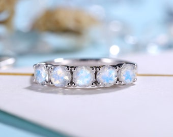 May include: A silver band ring with six round, iridescent moonstone gemstones set in a prong setting.