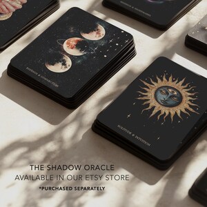 May include: A stack of black oracle cards with celestial illustrations. One card features three moons in a starry sky, another a sun with a face. Text on the cards reads "Endings & Connection" and "Solitude & Intuition". The text "The Shadow Oracle" is also visible.