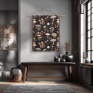 May include: A tapestry with a dark background featuring a repeating pattern of various mushrooms in shades of beige, brown, and orange. The tapestry is hung on a wooden rod and has a fringed edge.