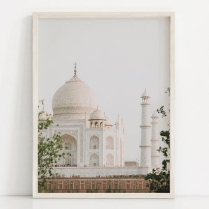 May include: A white marble building with intricate details, known as the Taj Mahal, is framed by lush green foliage. The building is a popular tourist destination in India.