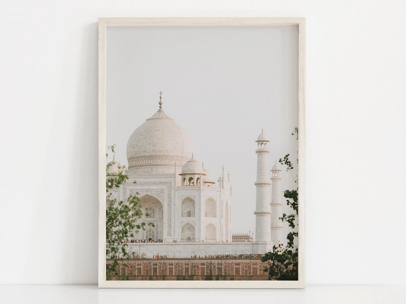 May include: A white marble building with intricate details, known as the Taj Mahal, is framed by lush green foliage. The building is a popular tourist destination in India.