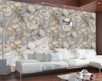 May include: A white sectional sofa with pillows sits in a living room with a large window overlooking a green lawn. The wall behind the sofa is covered in a floral wallpaper with a gray background and white flowers.