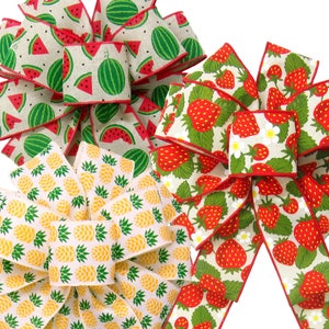 May include: Three fabric ribbon bows with summer fruit designs. The first bow is a watermelon print on a natural linen background. The second bow is a strawberry print on a natural linen background. The third bow is a pineapple print on a white background.