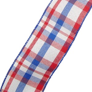 May include: Red, white and blue plaid ribbon with a white background. The ribbon has a woven texture and is edged with white stitching.