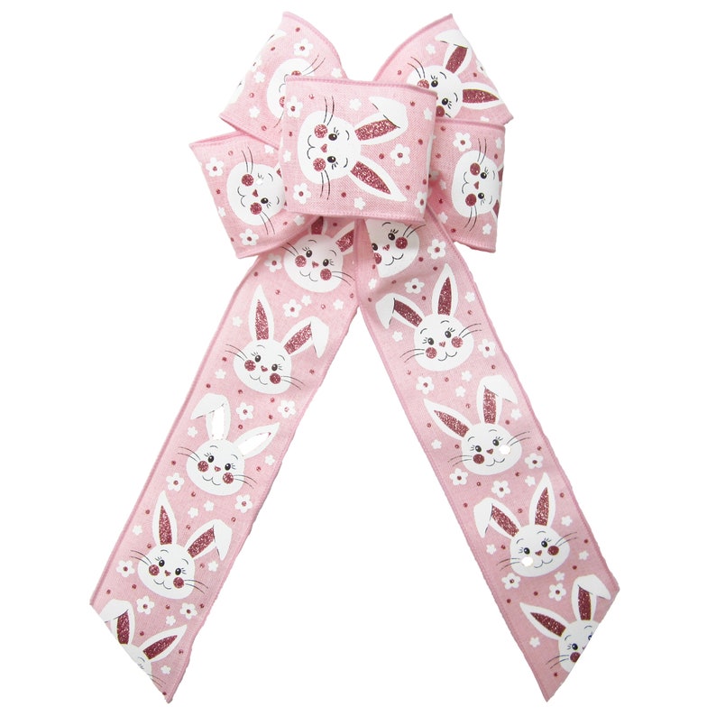 May include: A pink ribbon with a white bunny rabbit pattern. The ribbon is tied into a bow and is perfect for decorating for Easter.