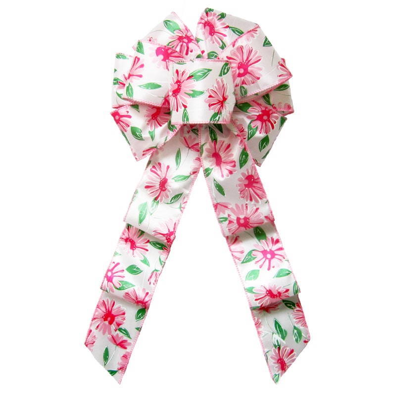 May include: A white satin bow with pink and green floral print. The bow is tied with a loop and tails.