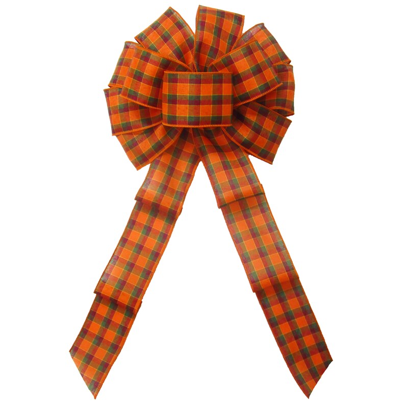 May include: A large, orange and green plaid bow with long tails. The bow is made of wired ribbon and is perfect for adding a touch of fall decor to your home.