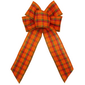 May include: A large, orange and green plaid bow with a wired edge. The bow is tied in a classic, symmetrical shape.