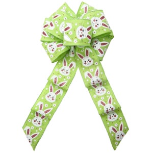 May include: A green and white ribbon bow with a repeating pattern of white bunnies with pink noses and white flowers. The bow is tied in a large, full loop.
