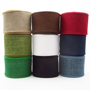 May include: Nine rolls of decorative ribbon in various colors, including tan, brown, red, green, white, navy, black, and denim blue. The ribbon has a textured appearance, suitable for crafts and gift wrapping.
