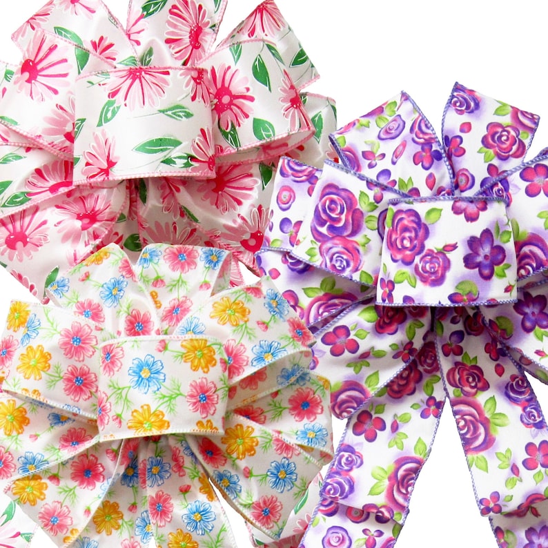 May include: Three floral patterned ribbon bows in pink, purple, and blue. The bows are made of satin ribbon and have a white background with colorful flowers.