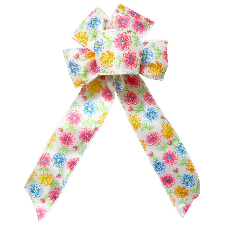May include: A white satin ribbon bow with a floral print featuring pink, yellow, and blue flowers. The bow is tied in a classic loop and tail style.