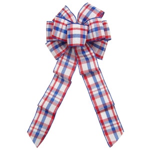 May include: A red, white and blue plaid bow with a wired edge. The bow is tied in a classic loop shape with two tails.