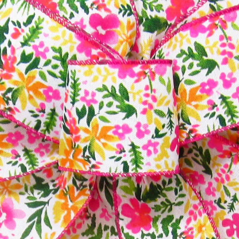 May include: White ribbon with a pink, orange, and green floral print. The ribbon has a pink edge.