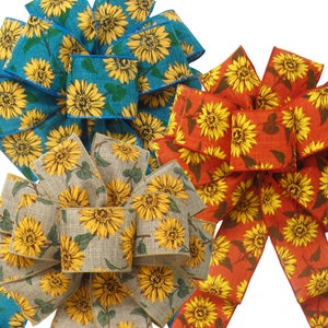 May include: Three sunflower patterned ribbon bows in teal, burlap, and red. The bows are tied together and ready to be used as a decorative element.