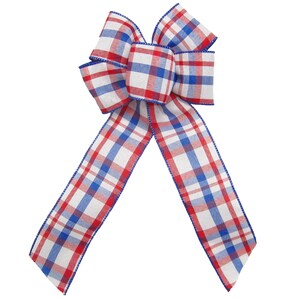 May include: A red, white and blue plaid bow with a wired edge. The bow is tied in a classic shape with two long tails.