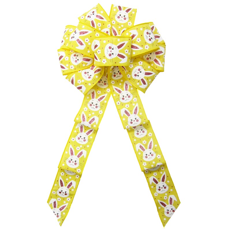 May include: A yellow bow with a white bunny rabbit pattern and pink glitter accents. The bow is tied with two long tails.