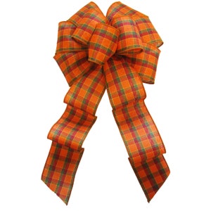 May include: A large plaid bow with orange, green, and red hues. The bow is made of wired ribbon and has a long tail.