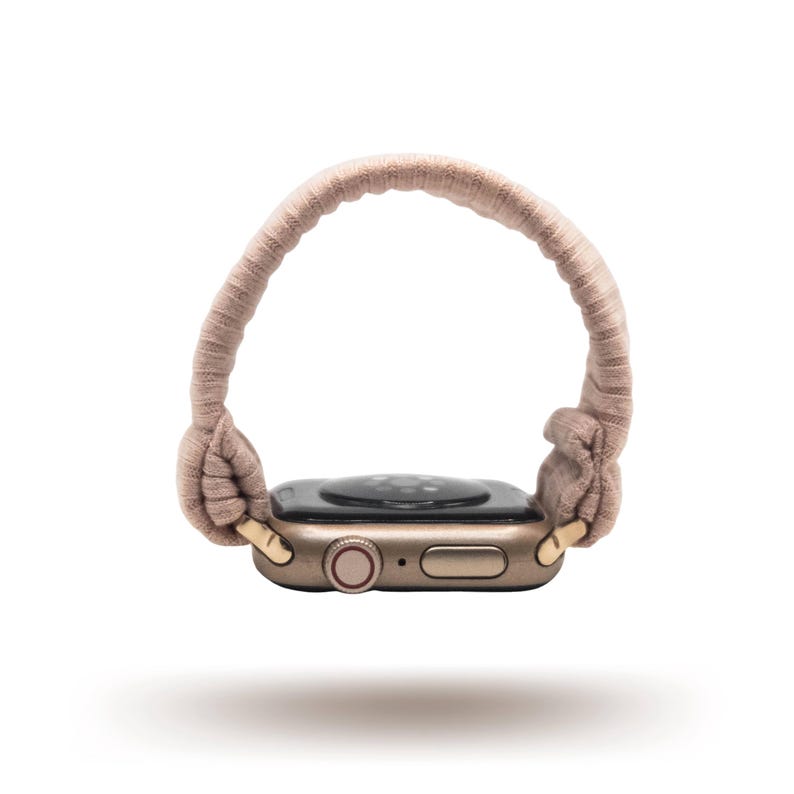 May include: A tan Apple Watch with a matching fabric band. The watch face is black, and the case is a gold color. The band is looped and knotted, creating a unique and stylish look.