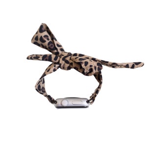 May include: A silver smartwatch with a leopard print fabric band. The band is tied in a bow at the top.