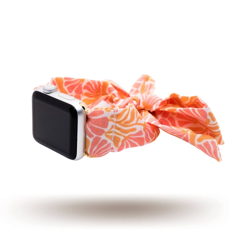 May include: A silver Apple Watch with a pink and orange floral patterned band. The band is tied in a bow.