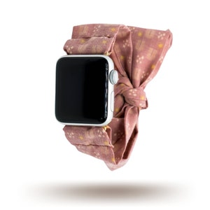 May include: A pink and white patterned fabric watch band with a silver Apple Watch.