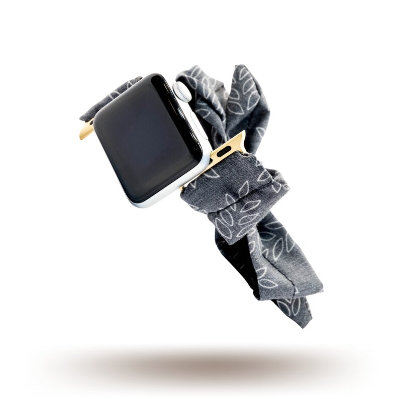 May include: A black and white patterned fabric watch band with a silver Apple Watch.