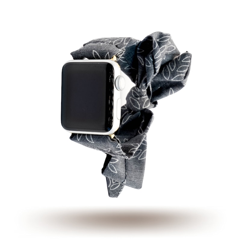 May include: A black and white patterned watch strap with a white Apple Watch face.