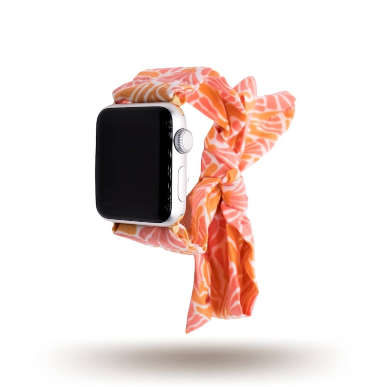 May include: A pink and orange patterned fabric watch band with a silver Apple Watch.