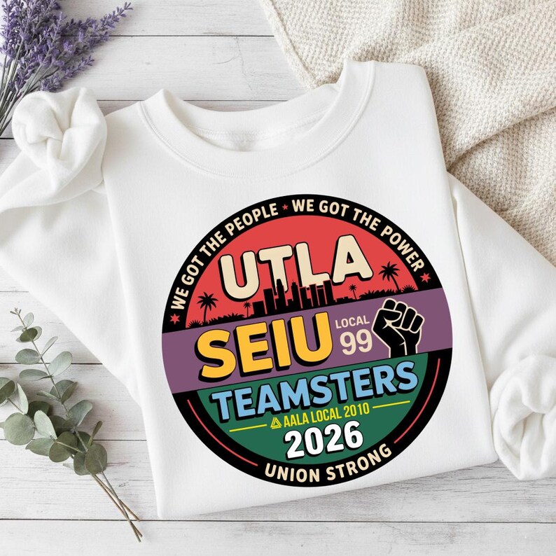 May include: White sweatshirt featuring a circular graphic with the text "UTLA SEIU TEAMSTERS Local 99" and "Union Strong." The design includes a cityscape silhouette, a raised fist, and the phrases "We Got The People" and "We Got The Power."